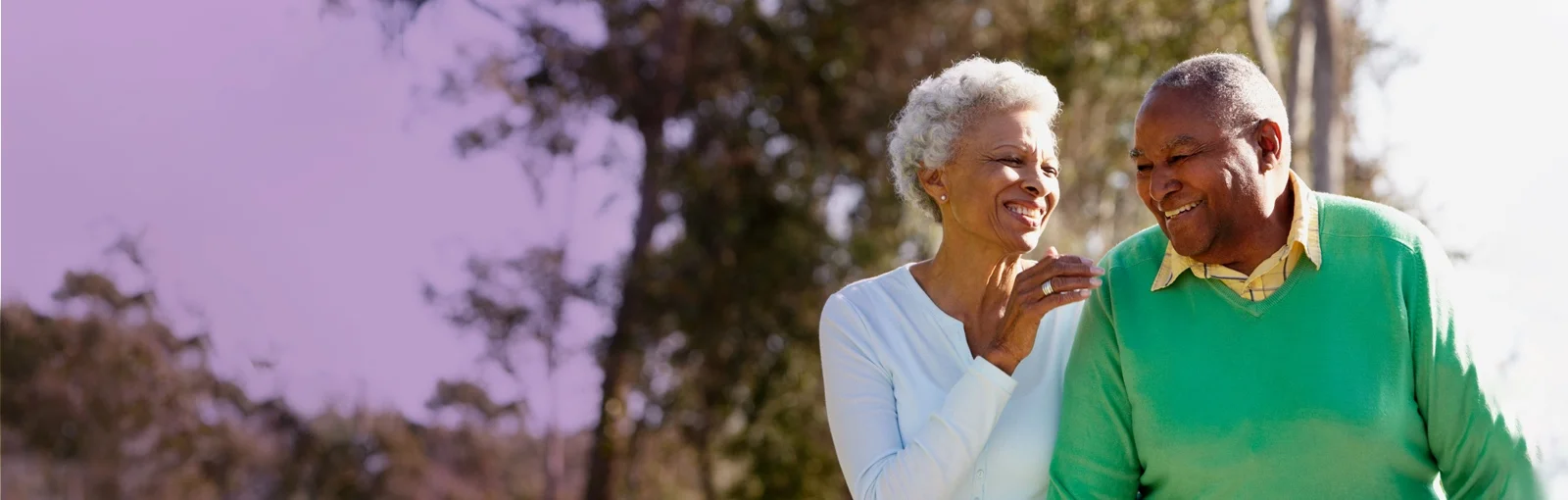 elderly couple walking through forest and smiling